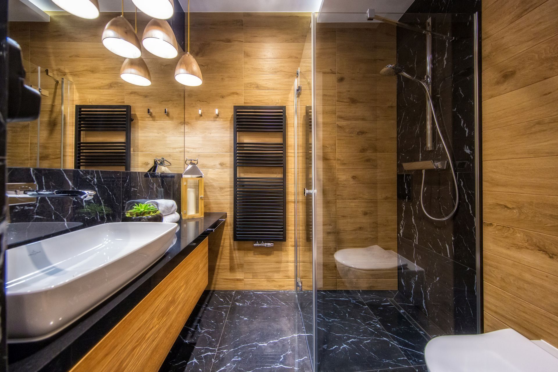 Een moderne badkamer met een houten wand, een douchecabine van glas, een marmeren vloer en een groot wastafel.