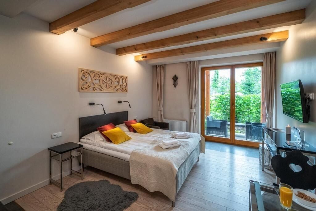 A modern bedroom with a bed, bedside table, and a view of a balcony.