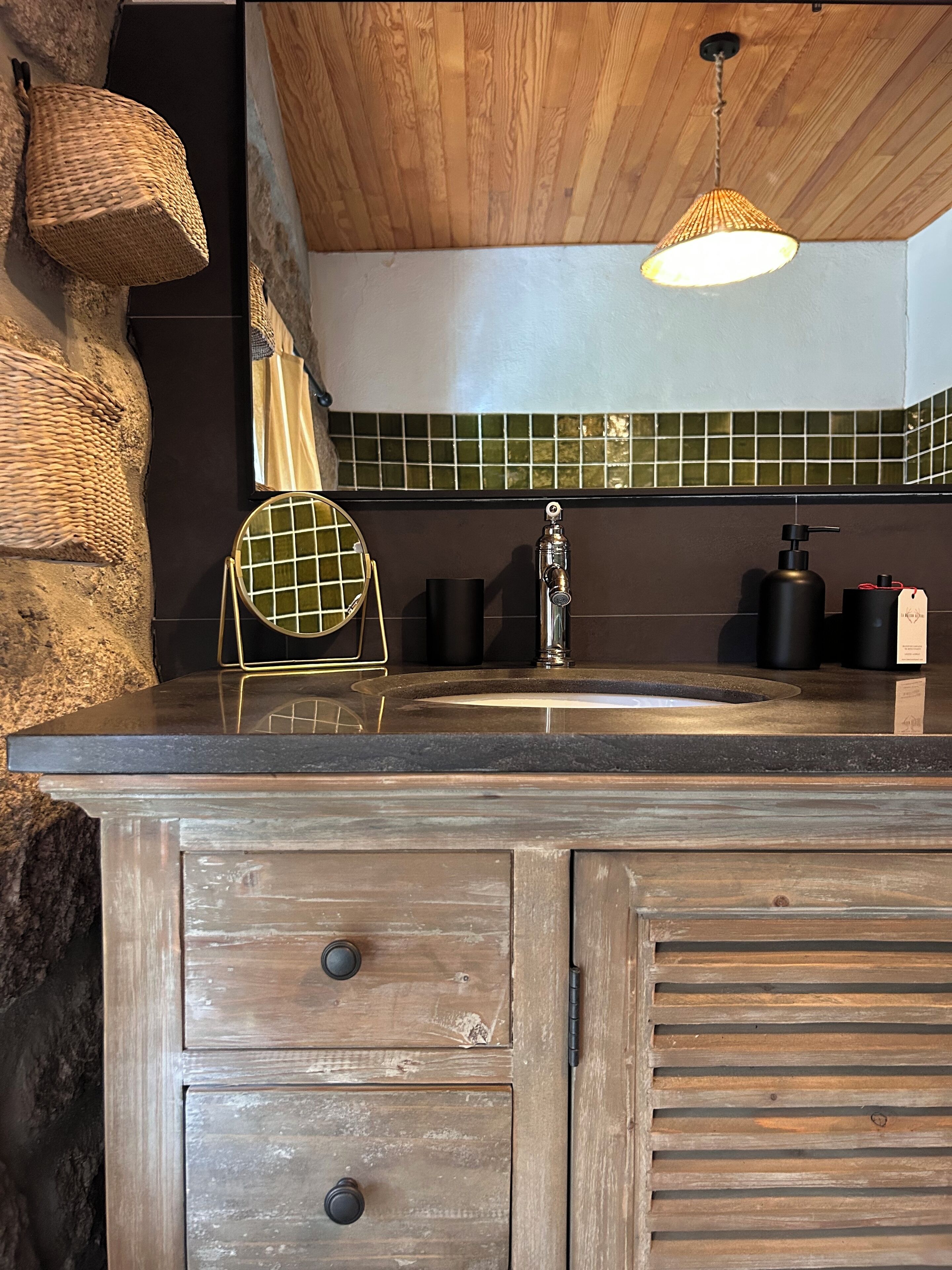 A kitchen with a stone accent wall, a wooden ceiling, and a green-tiled backsplash.