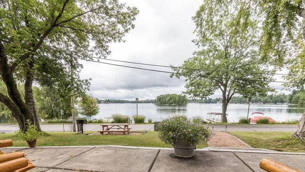 Un patio junto al lago con bancos de madera, una mesa de picnic y una planta en maceta.