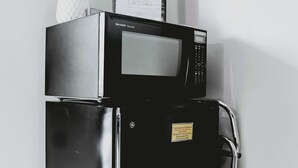 Un refrigerador negro con un microondas encima, un logotipo de GE y un cartel con información sobre el alquiler.