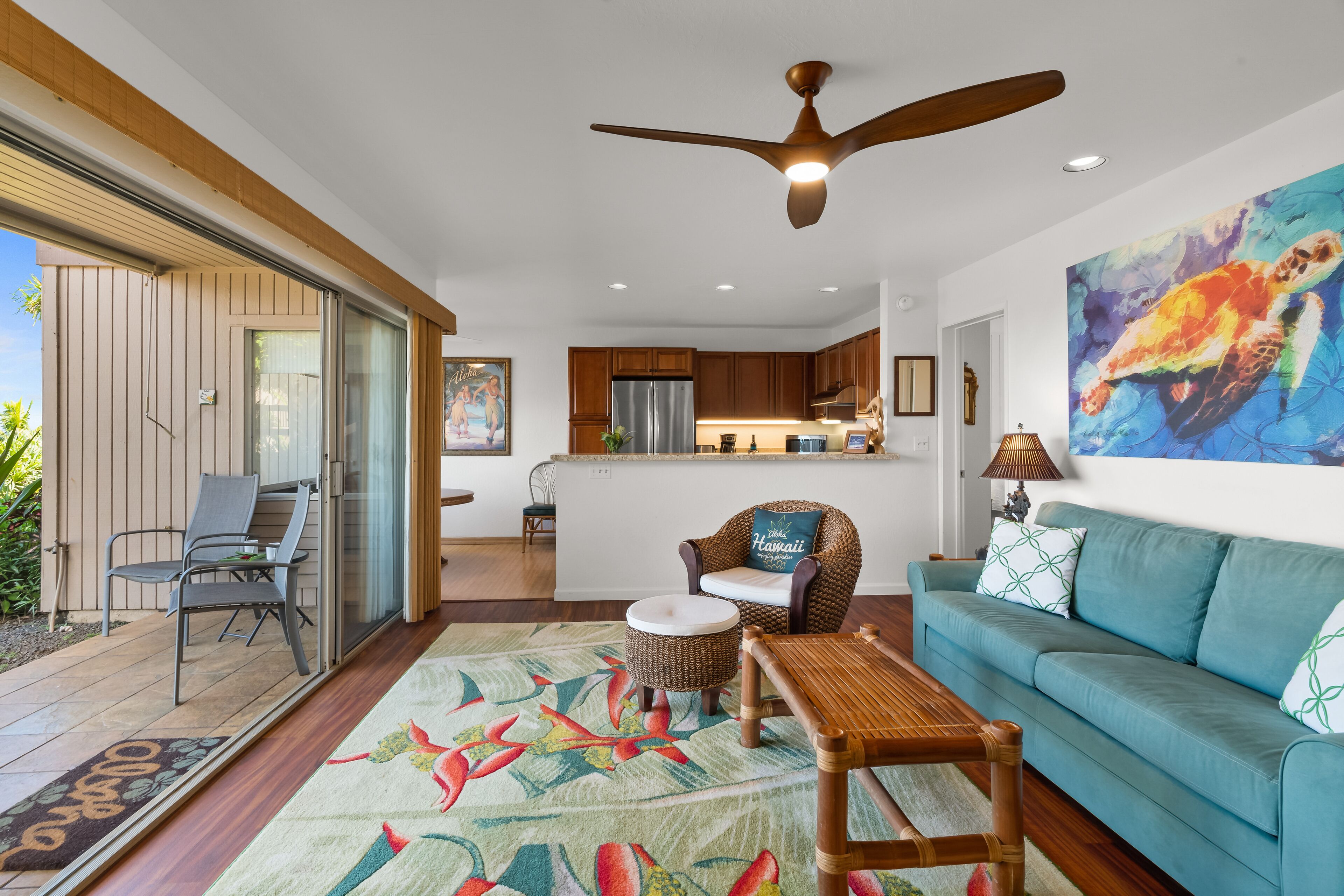 A modern living room with a teal sofa, a wooden coffee table, and a wicker chair.