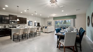 A modern kitchen with dark cabinets, a central island, and pendant lighting. - PROMO Magical 10 BR Villa, Pool/Spa, Resort - by Blue Sky Villas (Kissimmee)
