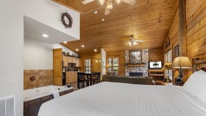 Une chambre spacieuse avec un grand lit, un plafond en bois et une cheminée en pierre.