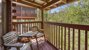 Une terrasse en bois avec une table et des chaises, donnant sur une cour clôturée et arborée.