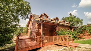 Une cabane en rondins avec un porche, une petite terrasse et une cour clôturée.
