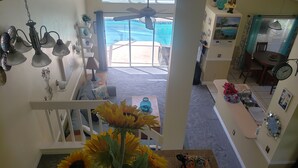 Un intérieur de maison comprenant un escalier, un coin repas et une vue sur un jardin avec une piscine.