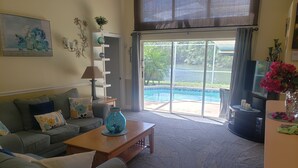 Un salon avec un canapé, une table basse et une vue sur une piscine extérieure.