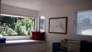 Ein modernes Wohnzimmer mit einer eingebauten Bank am Fenster, einer gerahmten Karte an der Wand und einem blauen Sofa.