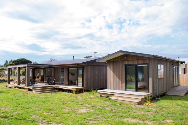 Eine moderne Holzhütte mit Terrasse, überdachter Veranda und einer großen Glasschiebetür zum Schlafzimmer.