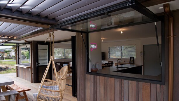 Eine moderne Küche mit einem großen Fenster, einem Hängekorbstuhl und einem Holzterrasse.