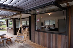 Une cuisine moderne avec une grande fenêtre, un fauteuil suspendu et une terrasse en bois.