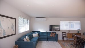Ein modernes Wohnzimmer mit einem blauen Modulsofa, einem weißen Teppich und einem Essbereich mit Holmöbeln.