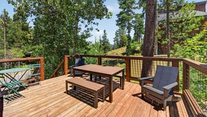 Une terrasse en bois avec une table et des chaises, entourée d’arbres.