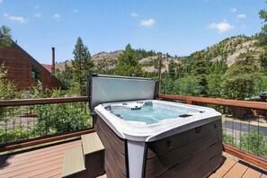 A hot tub on a wooden deck with a view of a mountainous landscape.