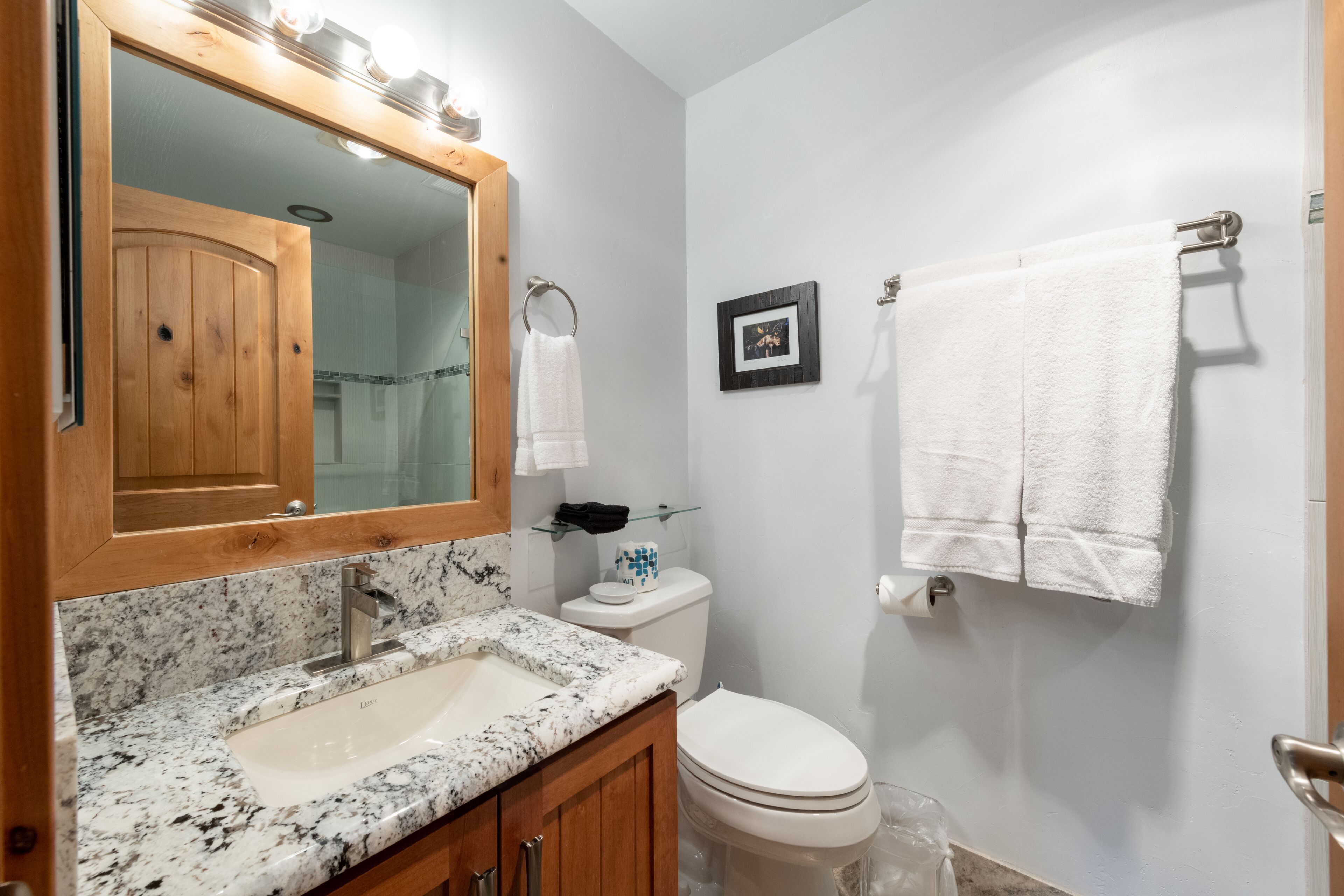 Une salle de bain avec un meuble-lavabo en bois, un lavabo, des toilettes et un porte-serviettes.