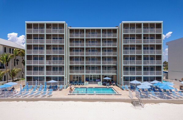 Un hôtel à plusieurs étages doté d’un espace piscine, comprenant des chaises longues et des parasols.