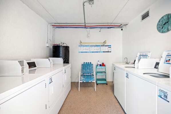 Un cuarto de lavandería con lavadoras, secadoras y un tanque de agua.
