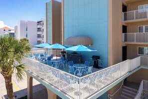 Un balcon avec coin salon extérieur, un barbecue et une piscine.
