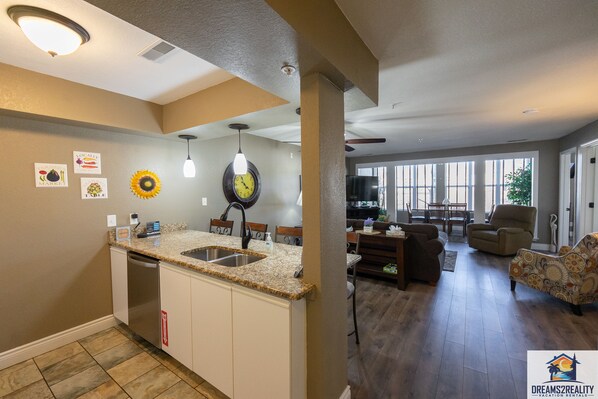 A modern kitchen with a granite countertop, stainless steel sink, and a built-in dishwasher.
