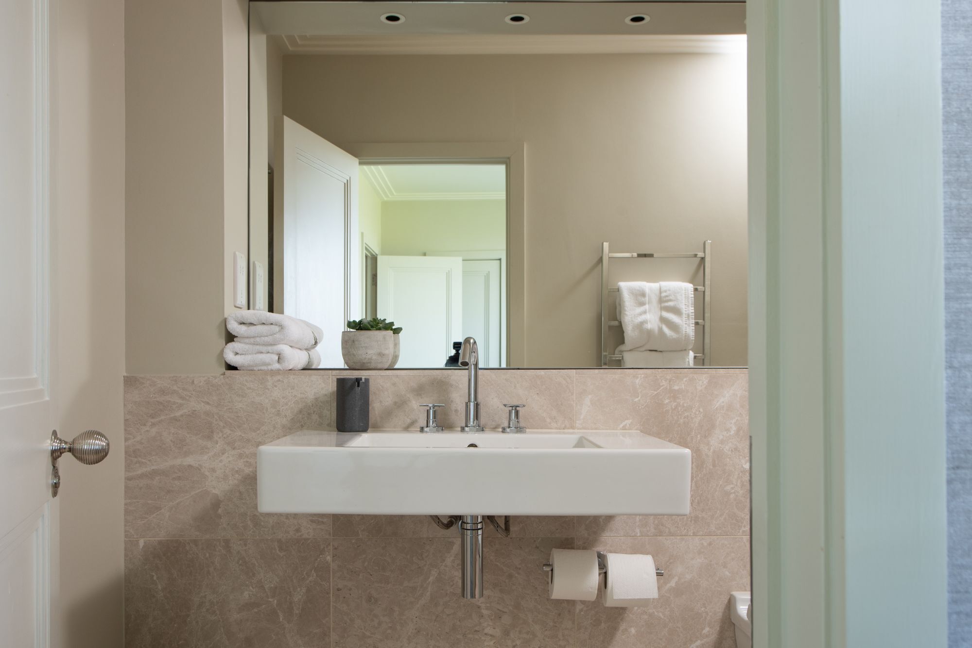 A bathroom with a white sink, a mirror, a towel rack, and a toilet.