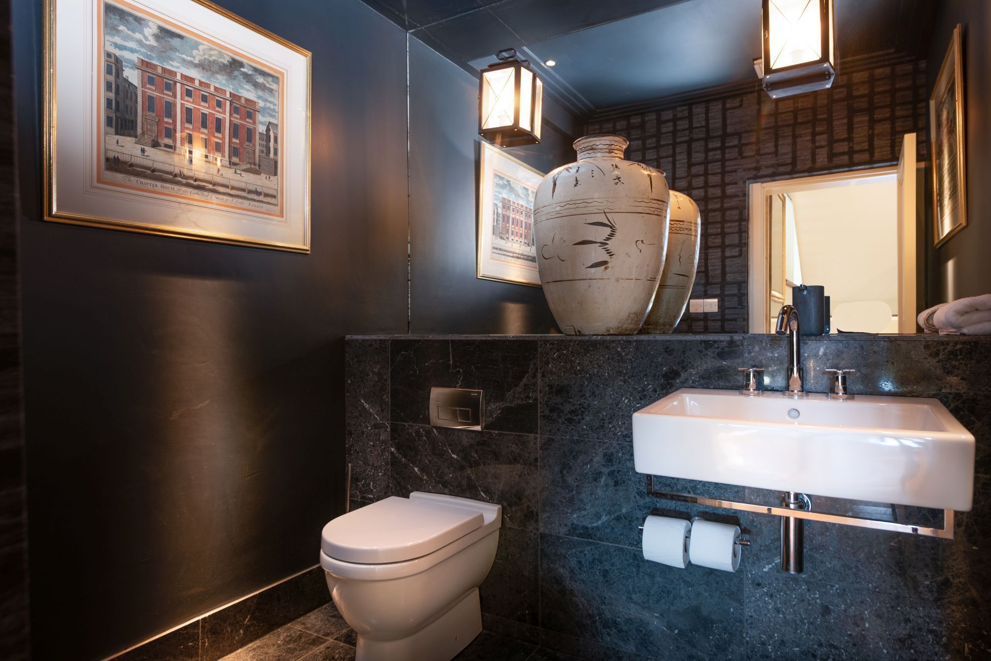 Un baño moderno con inodoro, lavamanos y un gran jarrón decorativo.