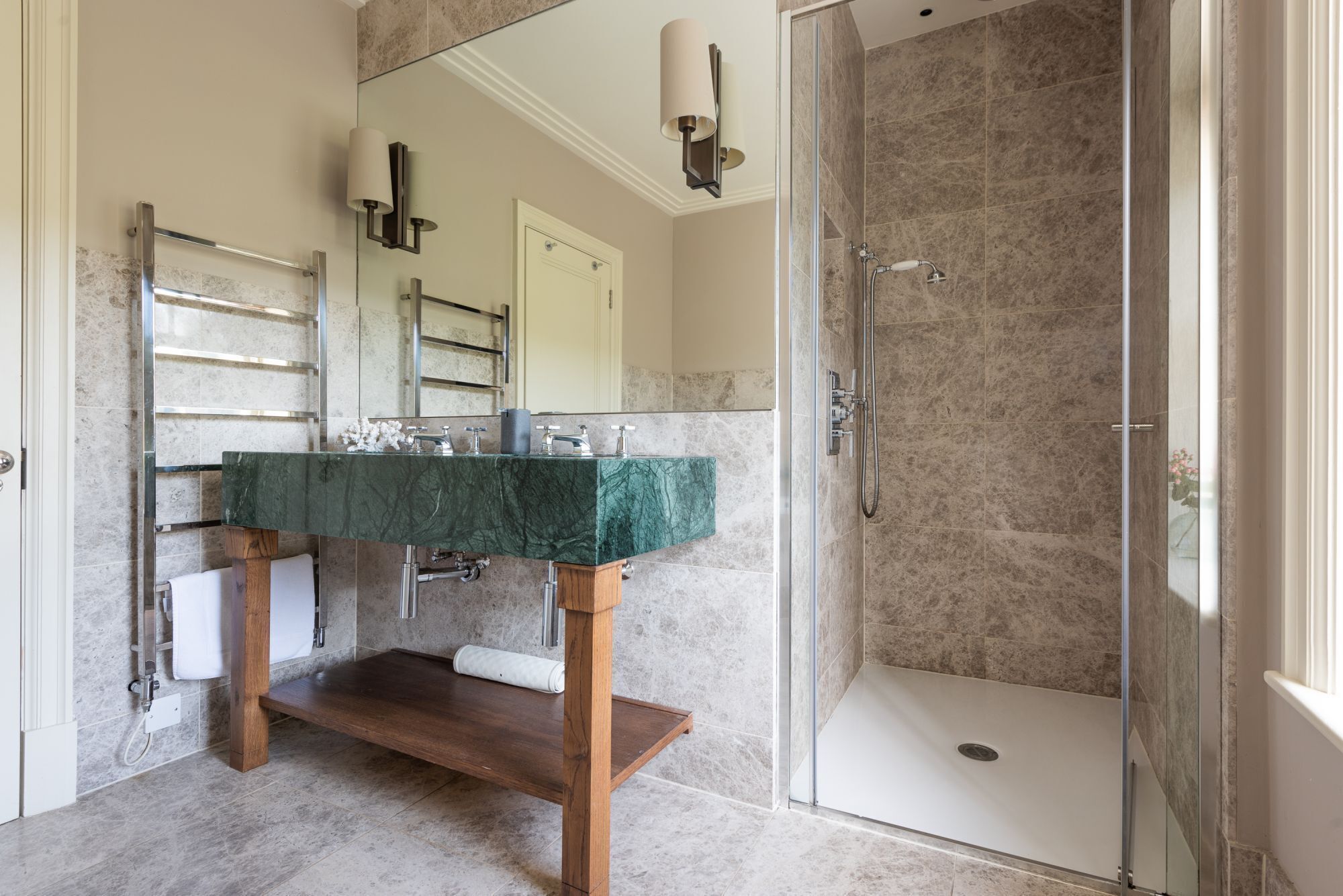 A modern bathroom with a marble sink, a glass-enclosed shower, and a wooden vanity.
