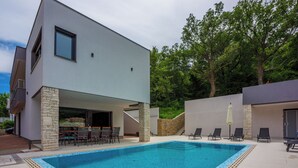 A modern building with a swimming pool, stone pillars, and outdoor seating. - Villa Adry (Bribir)