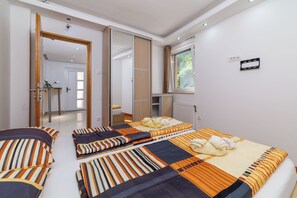 A hotel room with two beds, a large mirror, a window with a view, and a door leading to a bathroom. - Villa Adry 2 (Bribir)