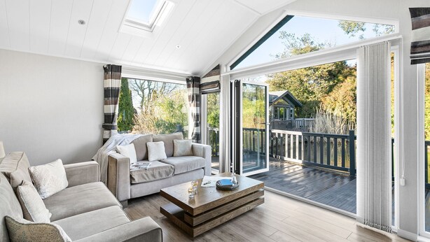 En rummelig stue med en stor sofa, et træbord og en skydedør, der fører til en terrasse.