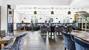 En restaurant med højt til loftet, synlige bjælker og forskellige siddepladser, herunder borde og båse.