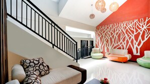 Un interior moderno con una escalera, un área de descanso y un muro decorativo.