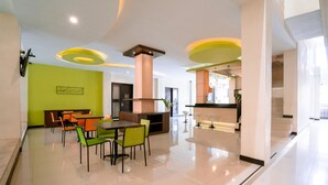 Un comedor moderno con una mesa central y sillas, una zona de cocina con estufa y una pared de acento verde brillante.