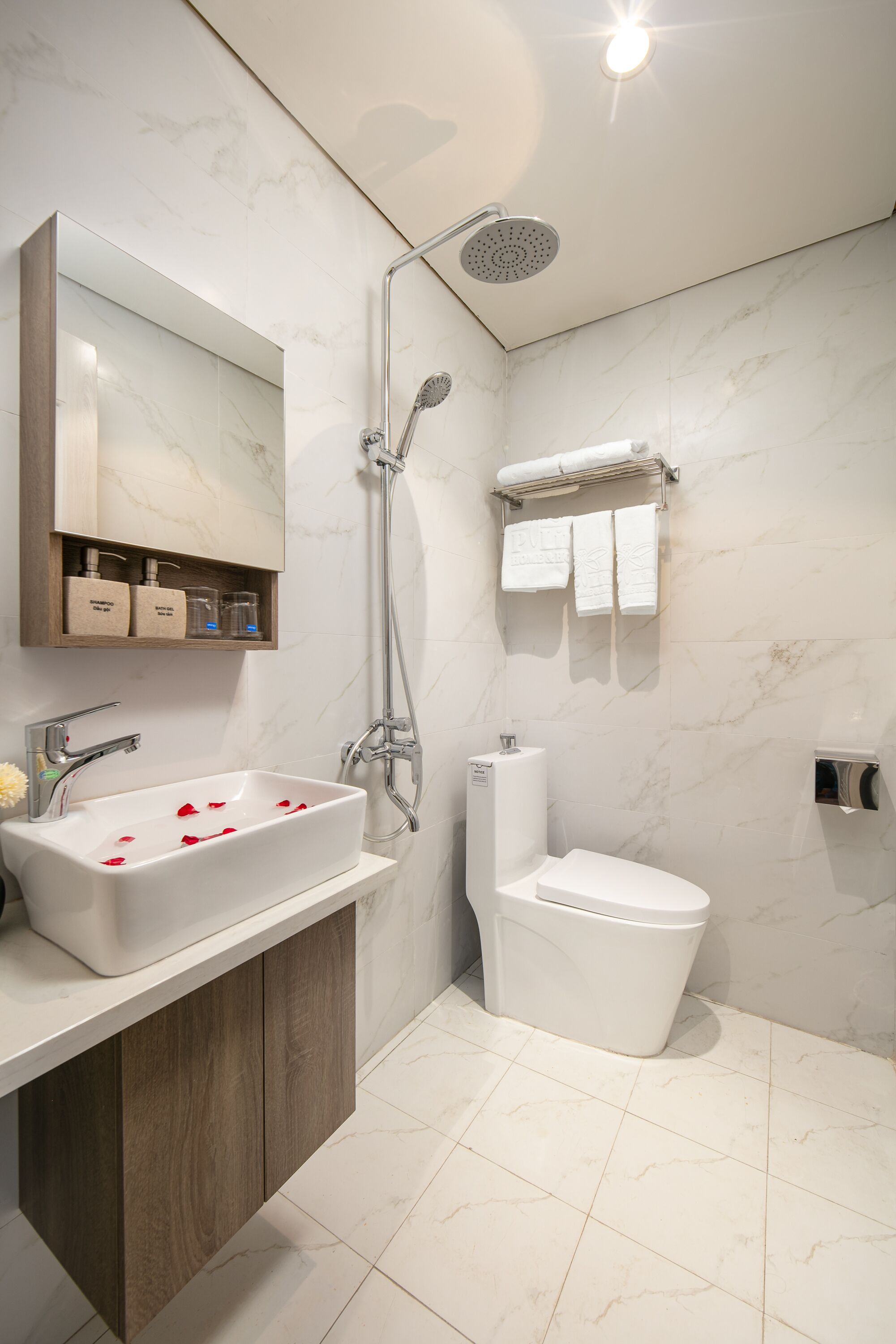 A modern bathroom with a marble sink, a shower, and a toilet.