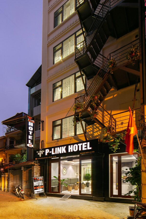 A hotel with a prominent sign, large windows, and a staircase leading to the upper floors. - P-Link Home & Hotel (Hanoi)