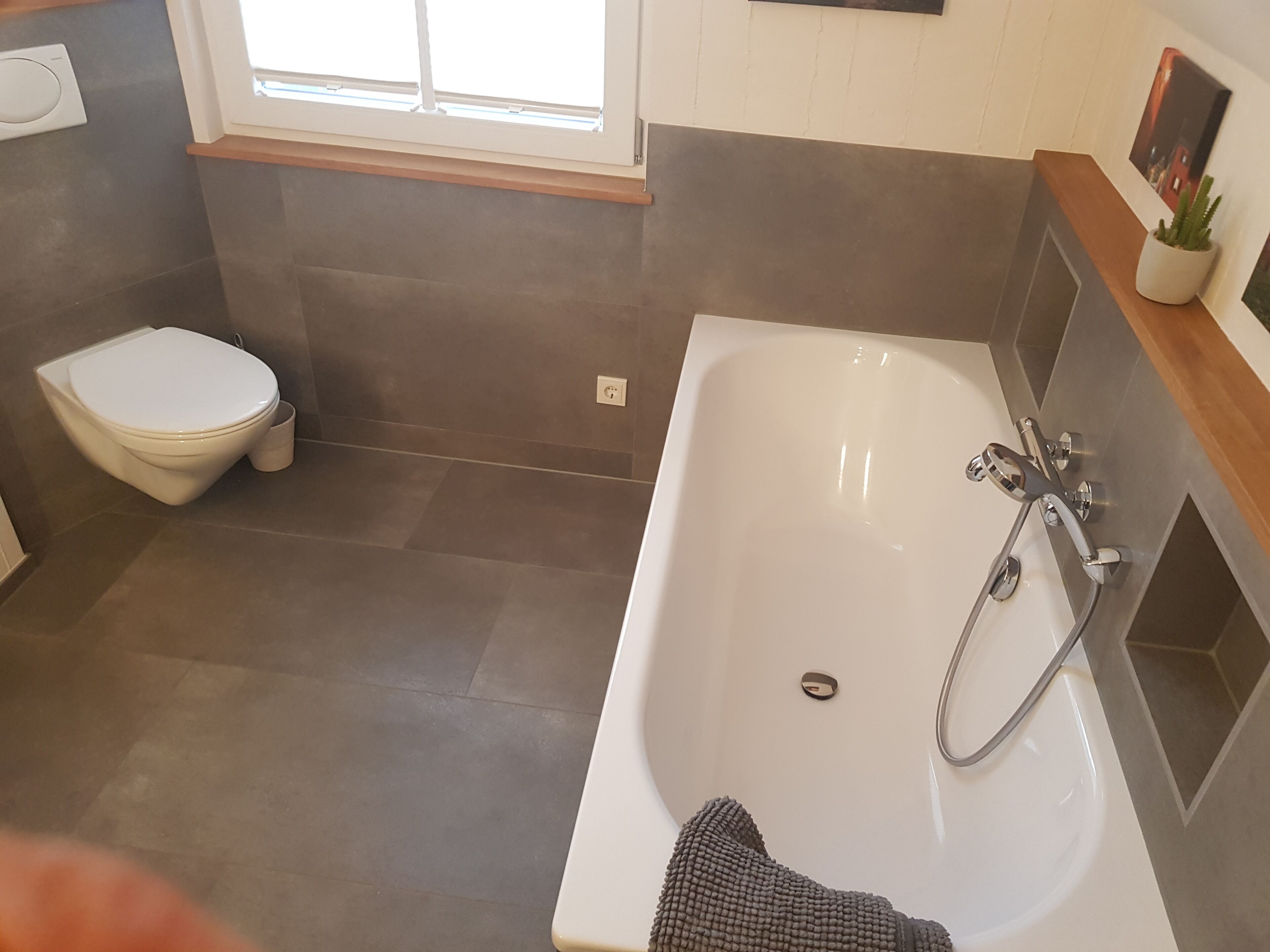 Un baño moderno con una bañera blanca, un inodoro y una ventana que proporciona luz natural.