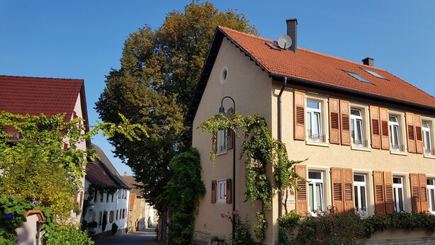 A narrow street lined with traditional European-style buildings, featuring red-tiled roofs and wooden shutters.