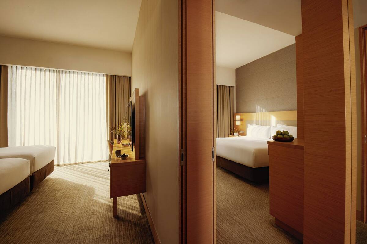 Une chambre d’hôtel avec un lit, un bureau, une chaise et une grande fenêtre avec des rideaux.