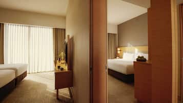 A hotel room with a bed, a desk, a chair, and a large window with curtains.