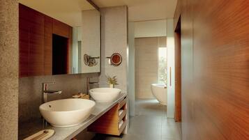 A modern bathroom with two sinks, a large mirror, and a bathtub.