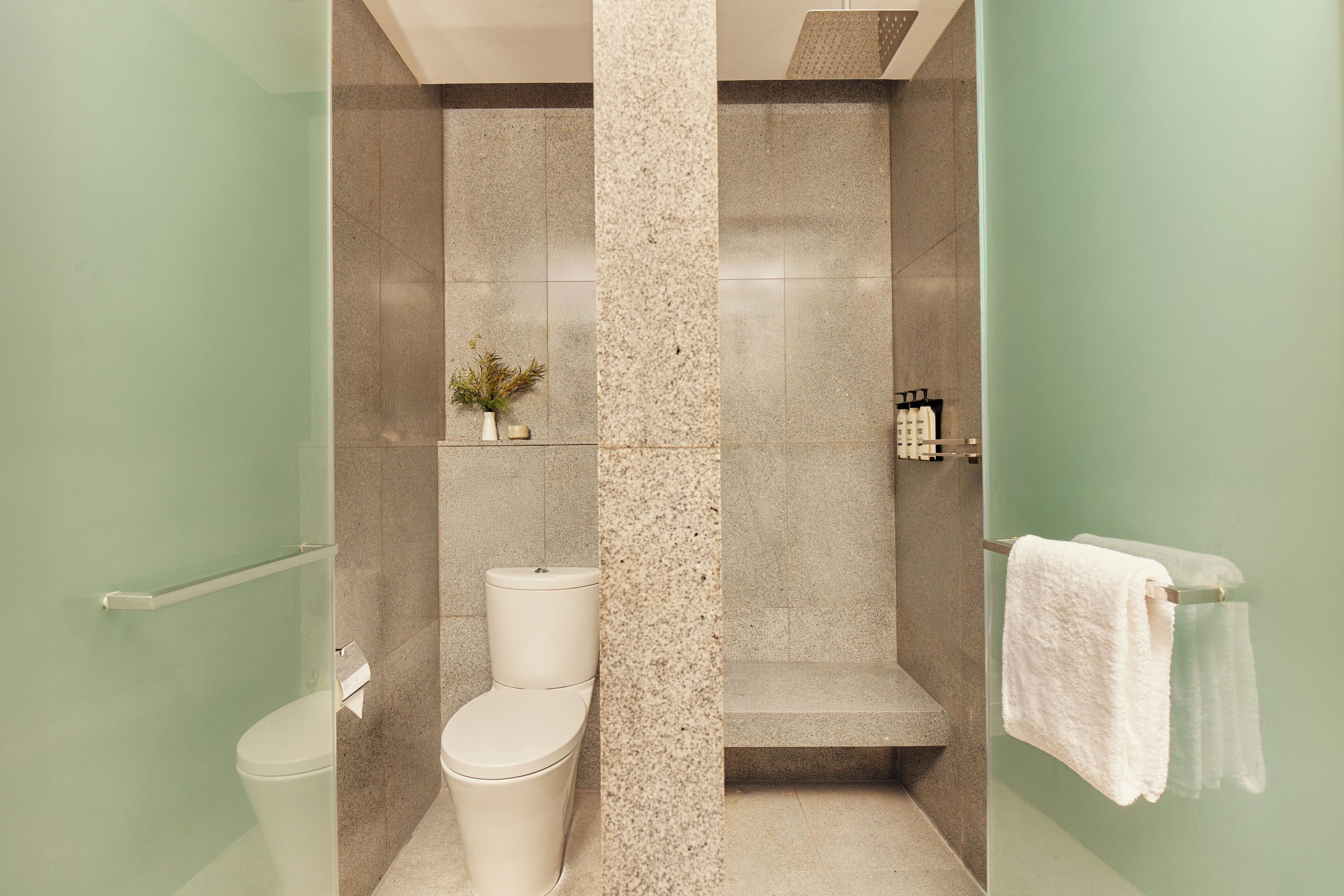 Un baño moderno con cabina de ducha de vidrio, inodoro y toallero.