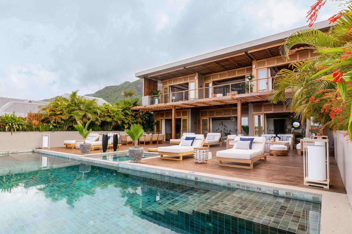 A modern resort with a pool, outdoor seating, and a two-story building.