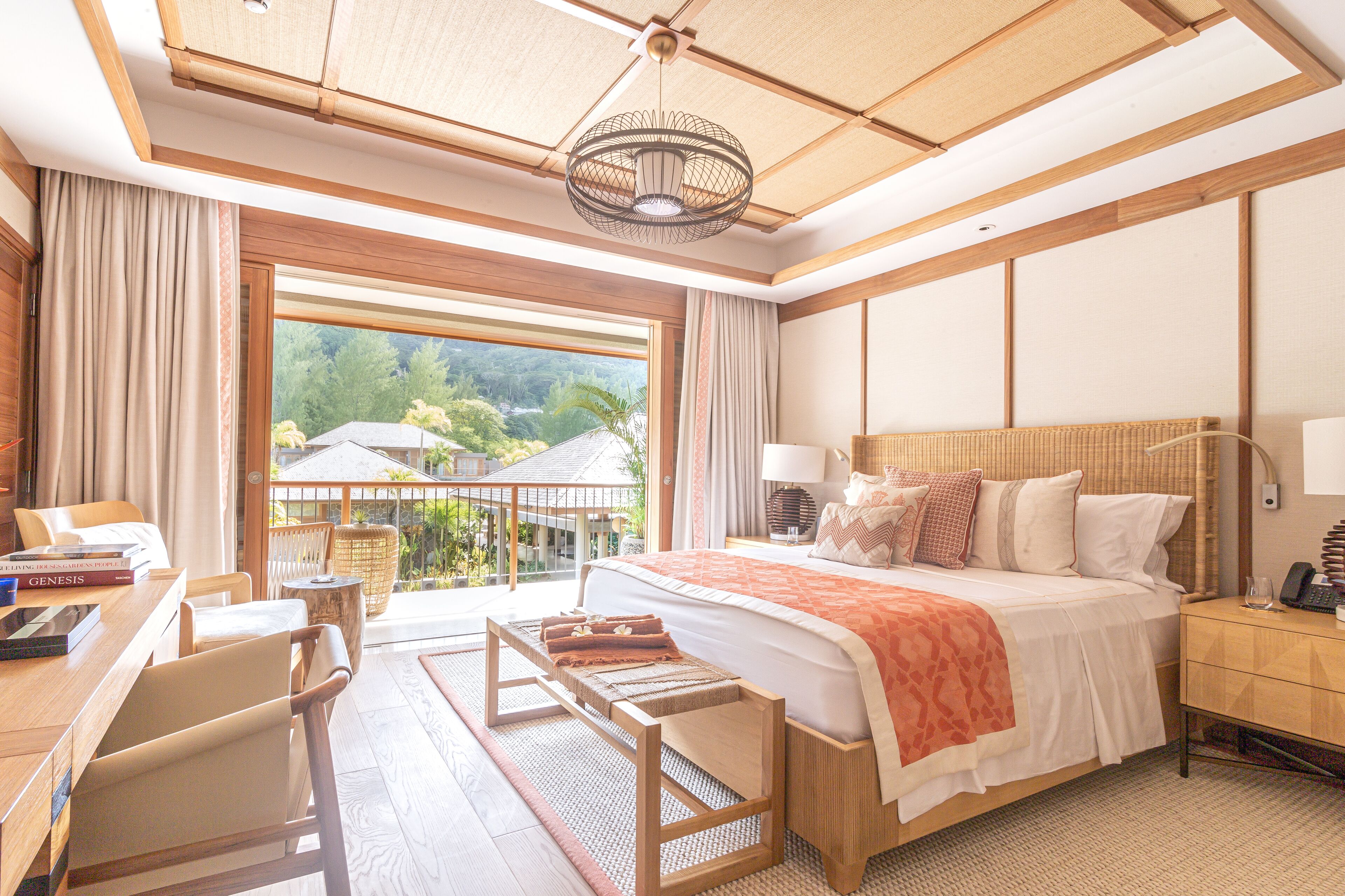A spacious bedroom with a large bed, a desk, and a view of greenery outside.