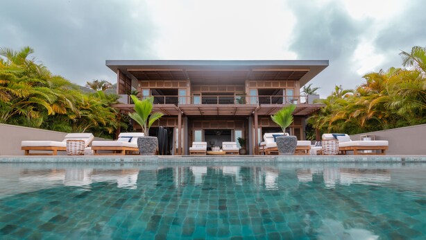 A modern hotel with a pool, lounge chairs, and palm trees. - L'Escale Resort Marina & Spa (Mahé Island)