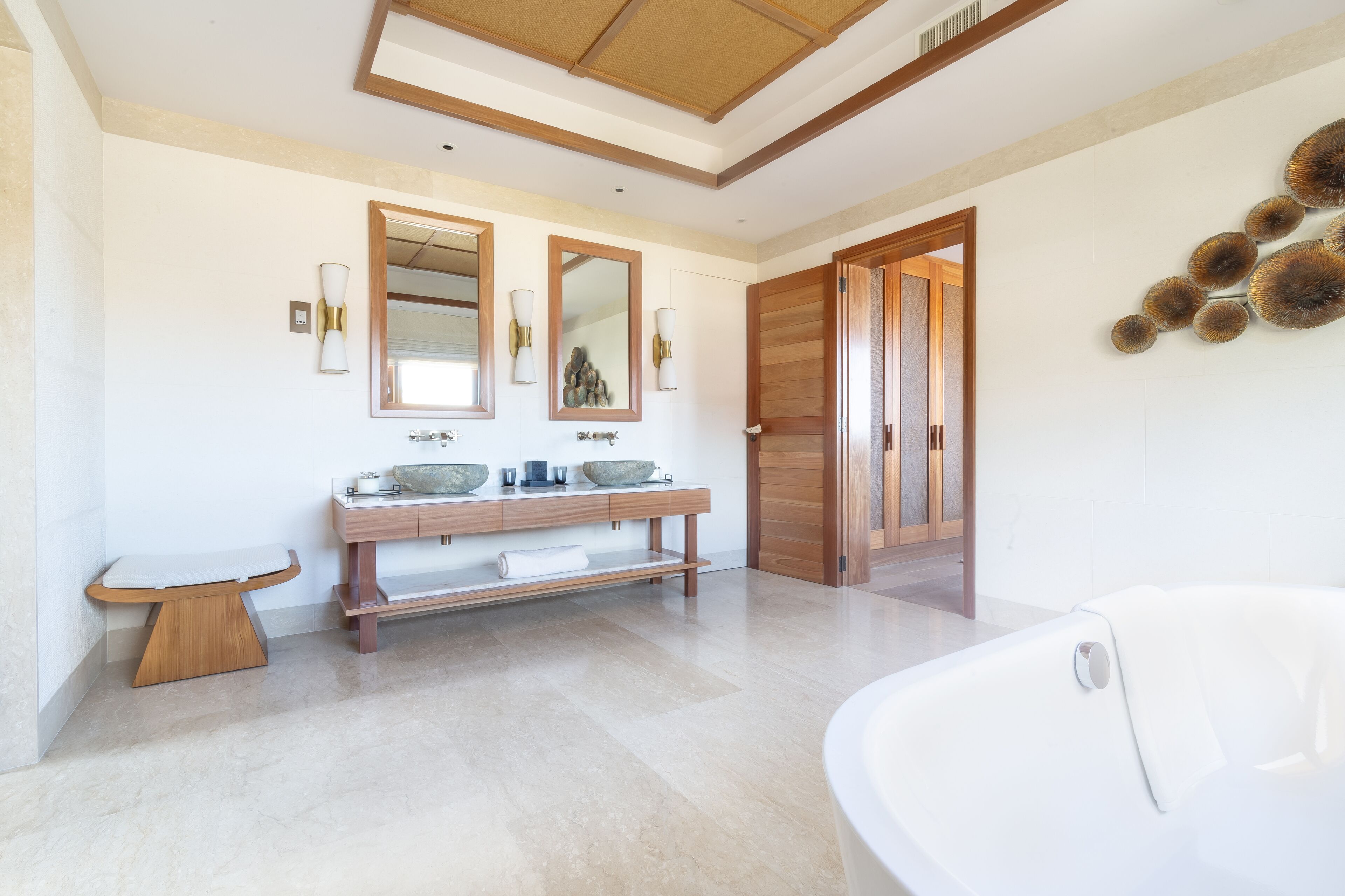 A modern bathroom with a large bathtub, a wooden vanity with two sinks, and a mirror above the vanity.