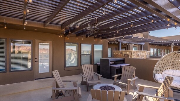 Un espace extérieur aménagé, abrité et doté de chaises Adirondack, d’un foyer et d’un bar.