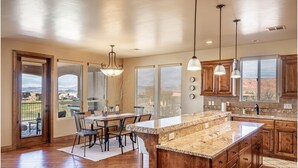 A spacious kitchen with wooden cabinets, a large island, and a view of the mountains. - Chip Shot (St. George)