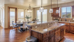 A spacious kitchen with granite countertops, wooden cabinets, and pendant lighting. - Chip Shot (St. George)