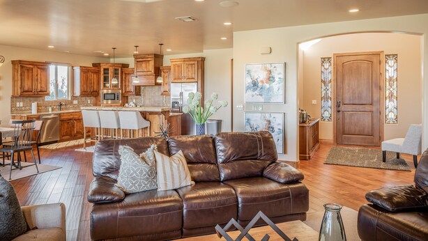 A spacious living area with a leather sofa, a dining table, and a kitchen in the background. - Chip Shot (St. George)