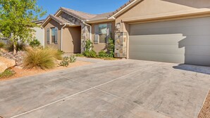 A modern two-story house with a stone facade, a garage, and a landscaped driveway.